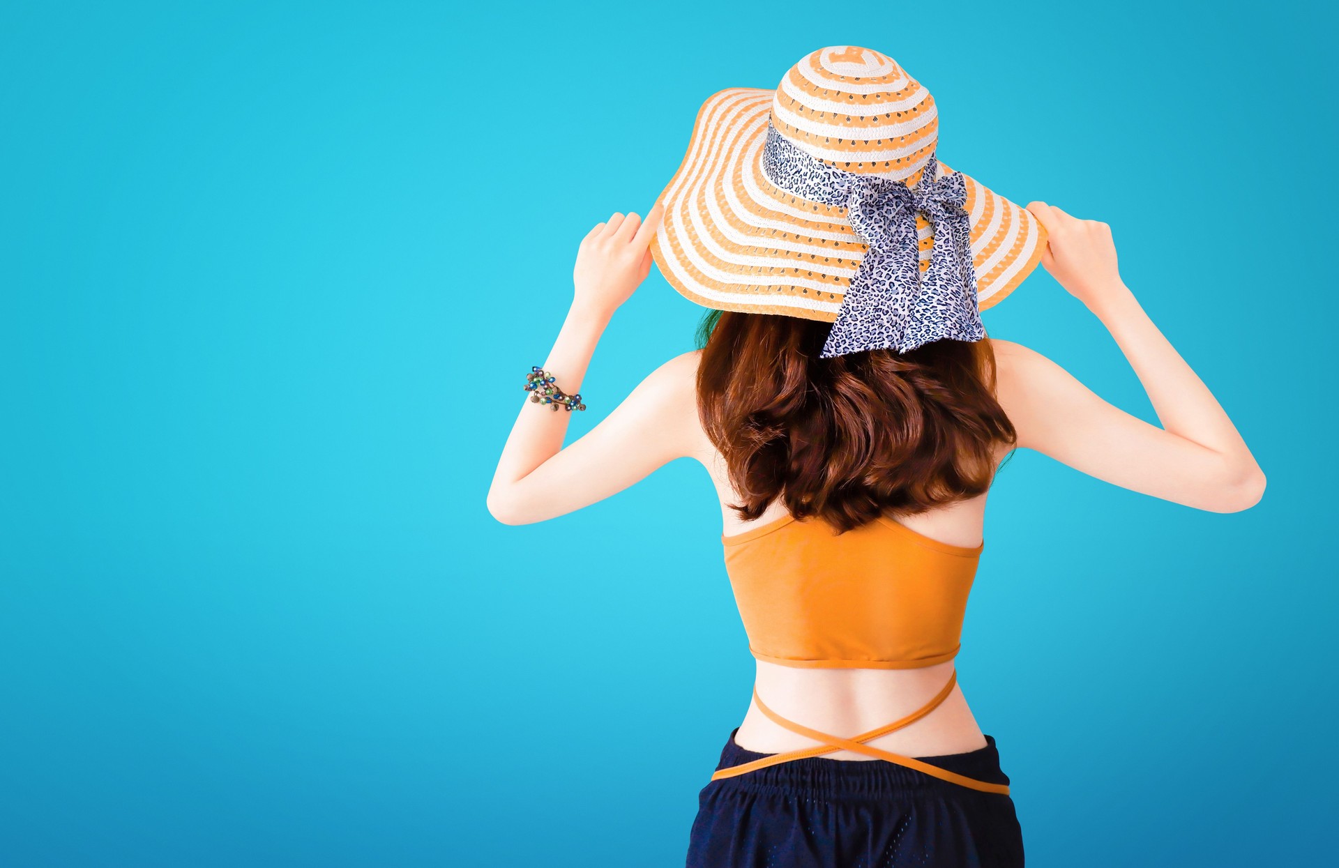 Beautiful pretty woman wearing a straw hat and sexy suit on blue background with Summer concept.